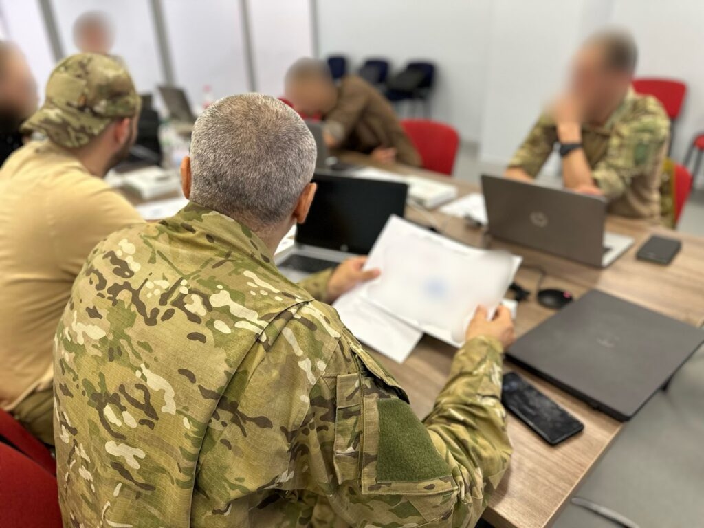 Робоча нарада: військові в камуфляжі за столом із ноутбуками та документами.