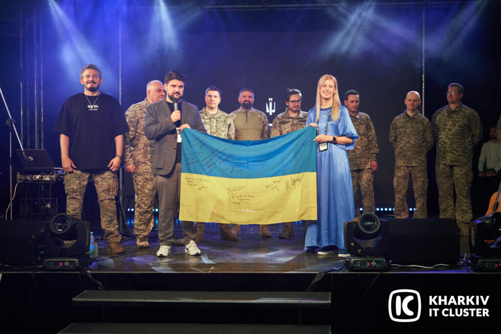 Учасники форуму Global Tech Kharkiv тримають підписаний прапор України